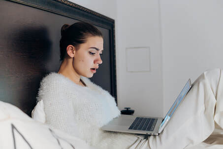 Woman watching Bridgerton, in bed, on her laptop. She is feeling physical arousal watching the sex scenes that encourage empowered female sexuality. You can get sex therapy in Plymouth, MN to learn more about how masturbation for women can help you feel more connected. Get help with sex therapy in Minneapolis and online therapy in Minnesota here.