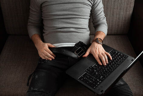 Picture of a man's body sitting on a couch with his pants unbuttoned and a computer on his lap. Symbolizing porn and masturbation...you can get porn addiction therapy in Plymouth, MN. Meet with a sex therapist for erectile dysfunction treatment minneapolis, mn here or via online therapy in Minnesota. 