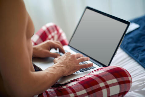 Picture of a man watching porn on his laptop in bed. Porn addiction, sex addiction, and out of control sexual behavior in Minnesota can be treated with a sex therapist in Plymouth, MN here. 55369 | 55361 | 55391