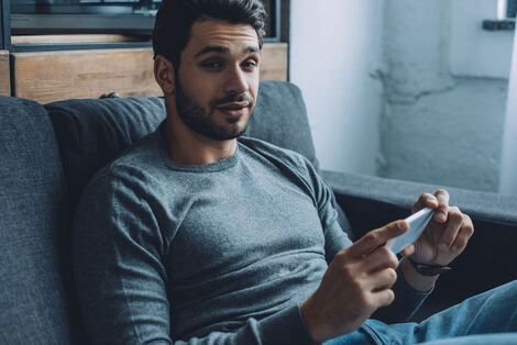 Picture of a man watching porn on his phone, looking up at the camera. Out of control sexual behavior in Minnesota, pornography addiction, sex addiction and substances can be helped via sex therapy in Plymouth, MN. 55447 | 55441 | 55442