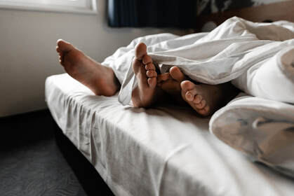 Picture of a couples' feet sticking out from under sheets, symboling the need for porn addiction therapy in Plymouth, MN for porn and masturbation. You can get assistance from a sex therapist with online therapy in Minnesota for erectile dysfunction treatment minneapolis, mn.