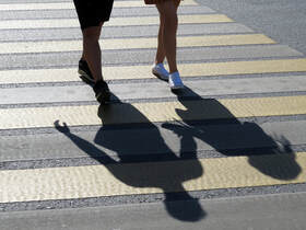 Photo of two people's legs, walking down the sidewalk holding hands. Their shadows extend out beyond their legs, showing the silhouette of a boy and a girl. Symbolizing childlike love and devotion for those considering marriage counseling in Plymouth, Minnesota. 
