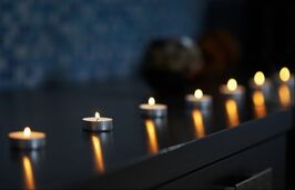 Line of lit tealight candles on a dark desk in a dark room, creating a peaceful environment for couples to connect in therapy with a Minneapolis area sex therapist.
