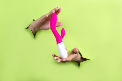 Picture of hands holding a rabbit vibrator sex toy with a green background. Are you looking for 