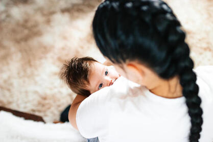 Woman holding baby, looking down into baby's eyes. Postpartum sex barriers can be discussed with a Plymouth, MN sex therapist here. Get couples therapy, marriage counseling, relationship counseling and more with online therapy in Minnesota.