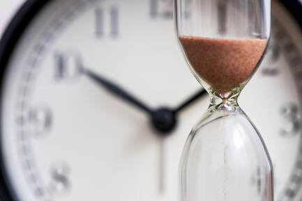 Picture of an hourglass in front of a clock. Lasting longer in bed can happen with tips from a sex therapist in Minneapolis, MN based in this Plymouth, MN counseling center for online therapy in Minnesota.