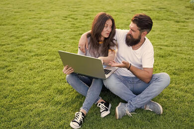 Picture of couple on computer outside in the grass. Couples therapy in Plymouth, MN or sex therapy in Minneapolis, MN can help you learn more. Meet with a sex therapist with online therapy in Minnesota here.